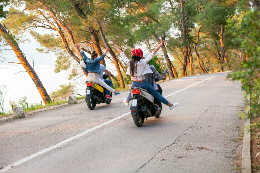 Couples enjoying a moped ride on a scenic road in Crete